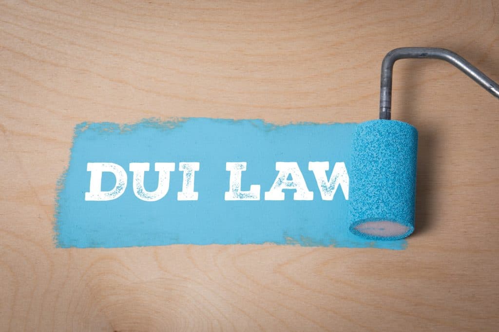 Blue paint roller with 'DUI LAW' text on wooden surface.
